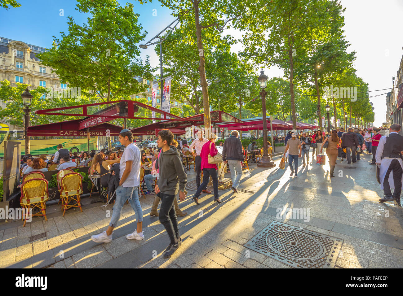Paris, France - July 2, 2017: tourists walk on the most famous avenue of Paris, the Champs Elysees, for shopping in luxury shops. Lifestyle people sitting at Cafe George V. Stock Photo