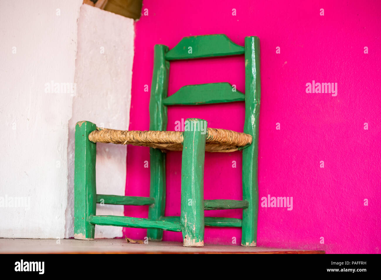 Green wooden chair on a pink wall background, Santo Domingo, Dominican