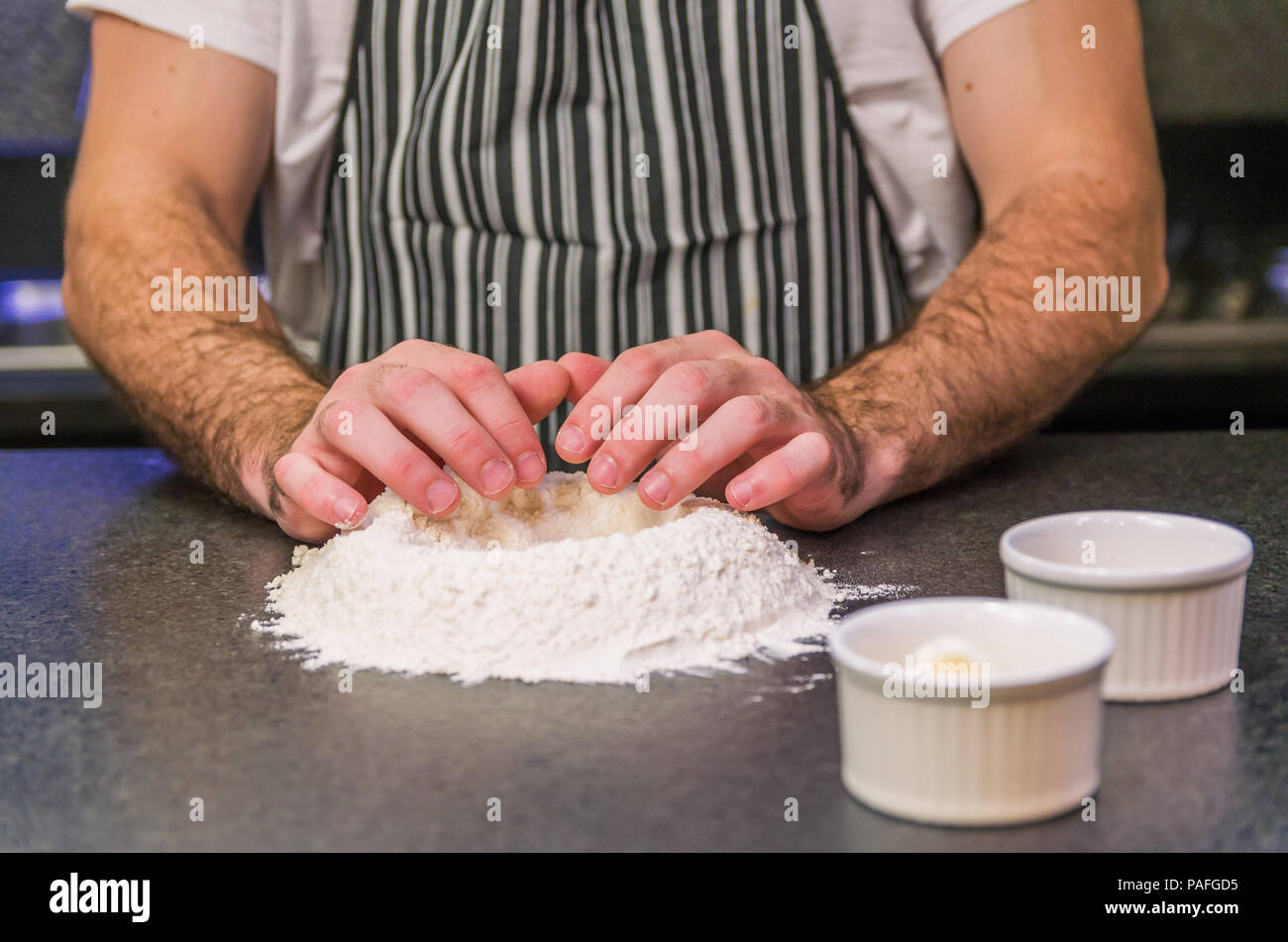Man preparing pizza dough on black granite table Stock Photo