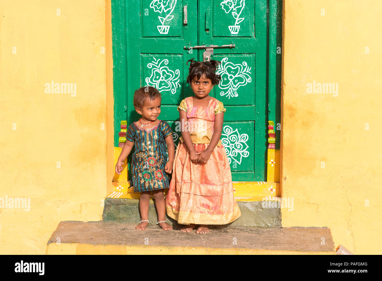 PUTTAPARTHI, ANDHRA PRADESH, INDIA - JULY 9, 2017: Two little indian girls on the doorstep of a house. Copy space for text Stock Photo