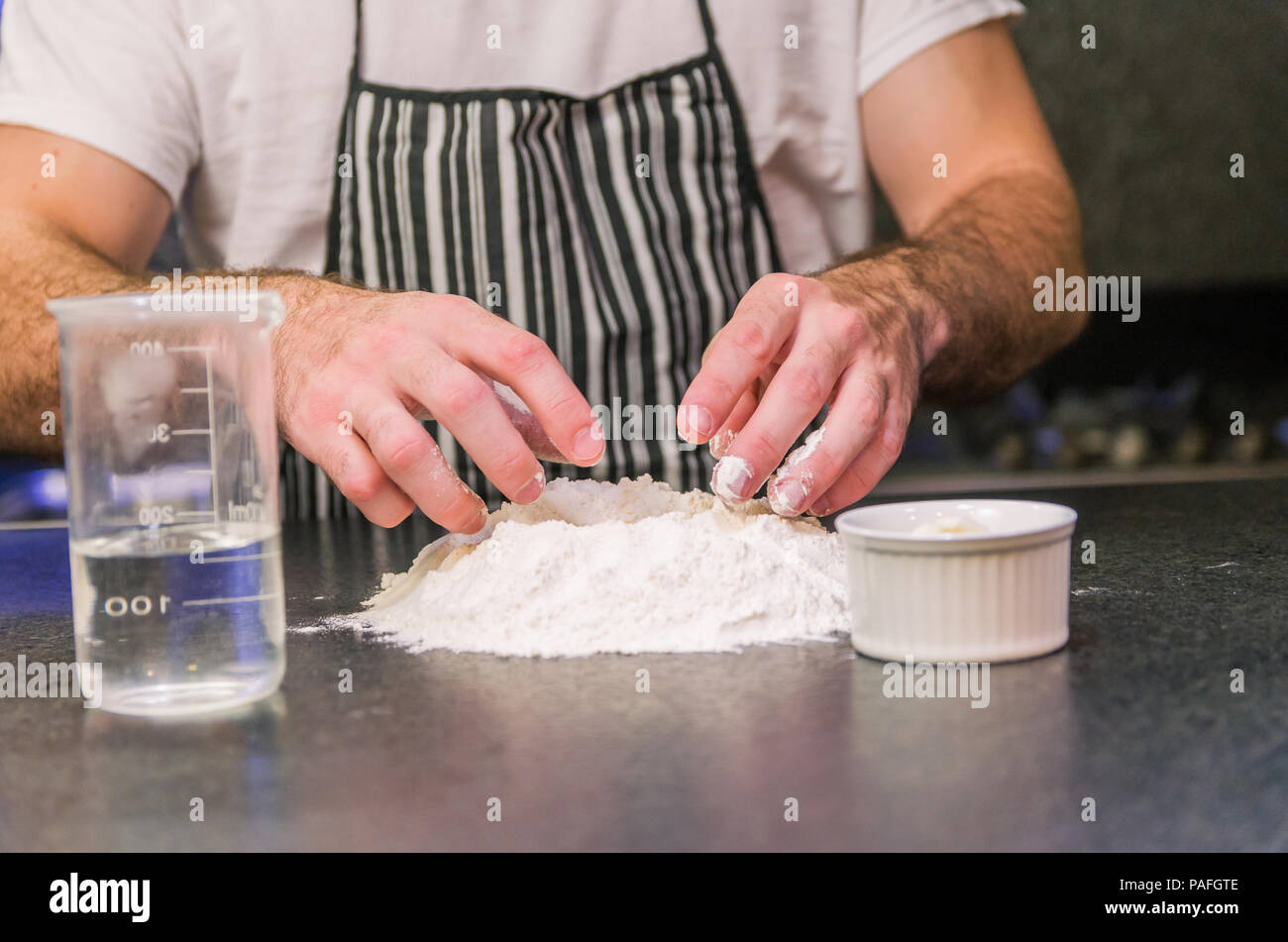 Man preparing pizza dough on black granite table Stock Photo