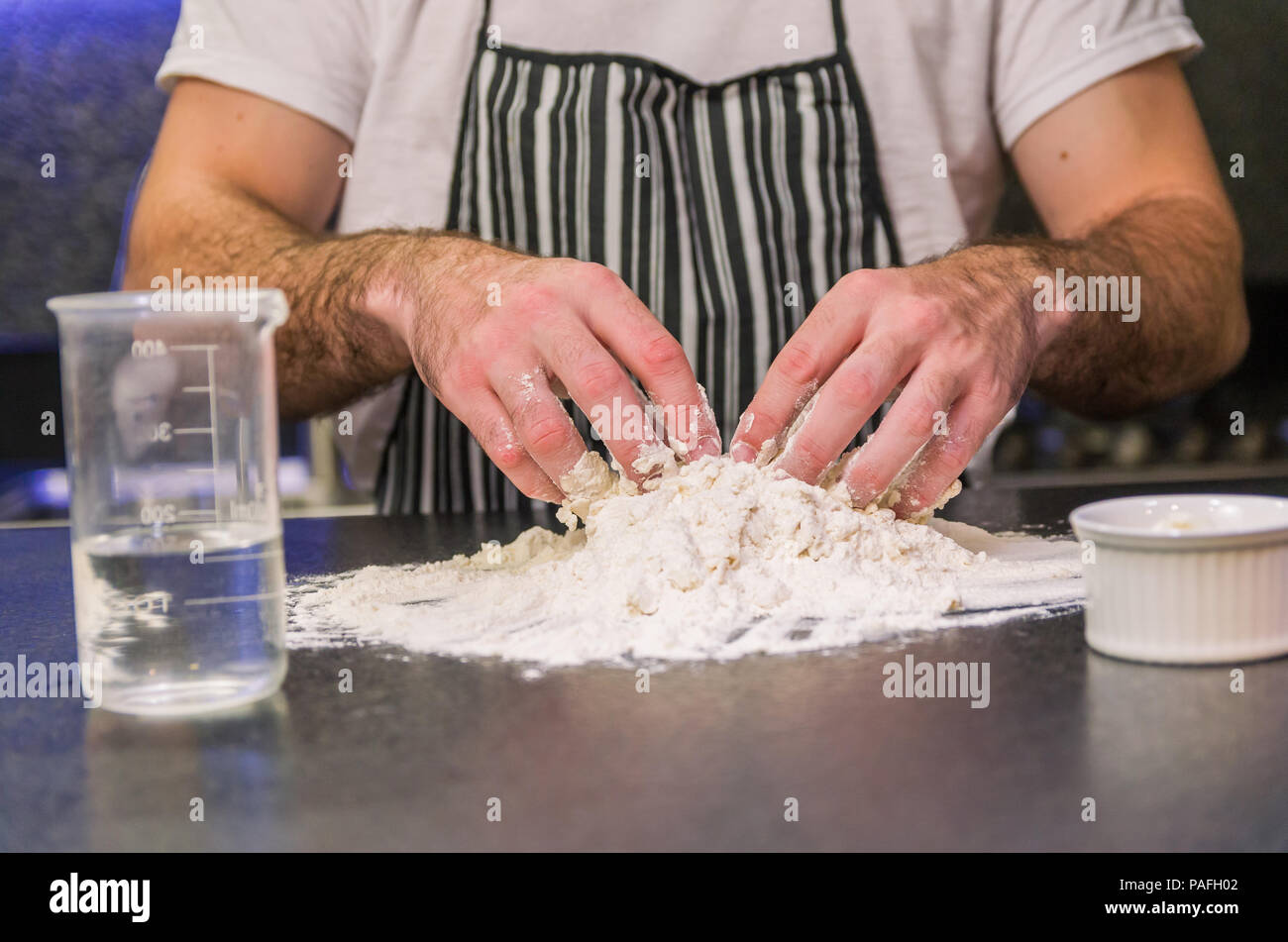 Man preparing pizza dough on black granite table Stock Photo
