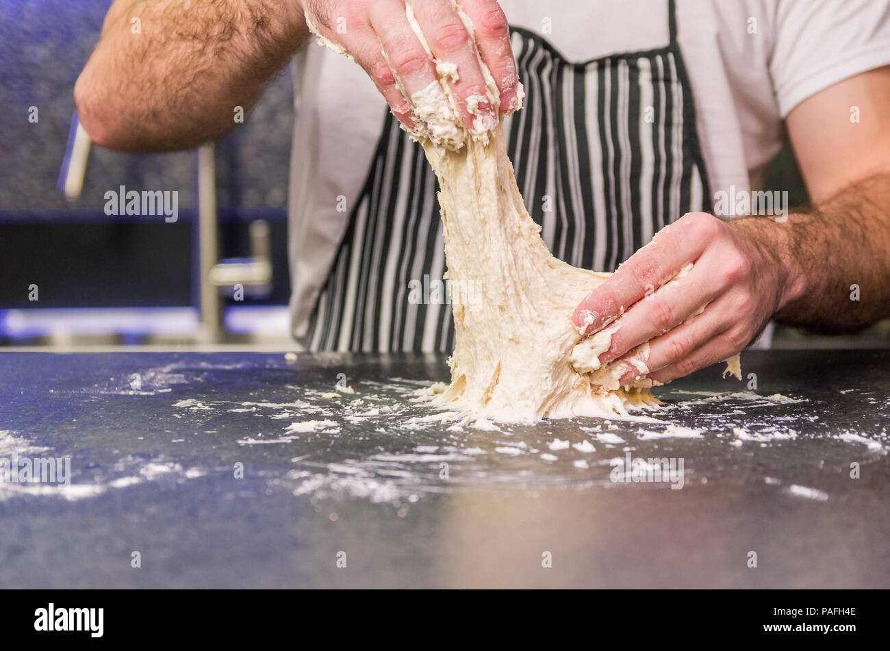 Man preparing pizza dough on black granite table Stock Photo