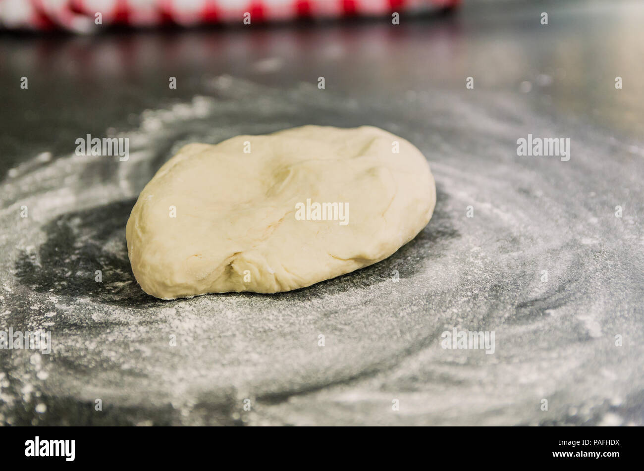 Mound of wheat flour on top of black granite table, preparation of