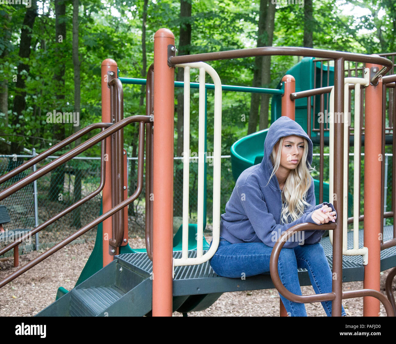 Teenage girl sitting at a playground in a sullen mood Stock Photo
