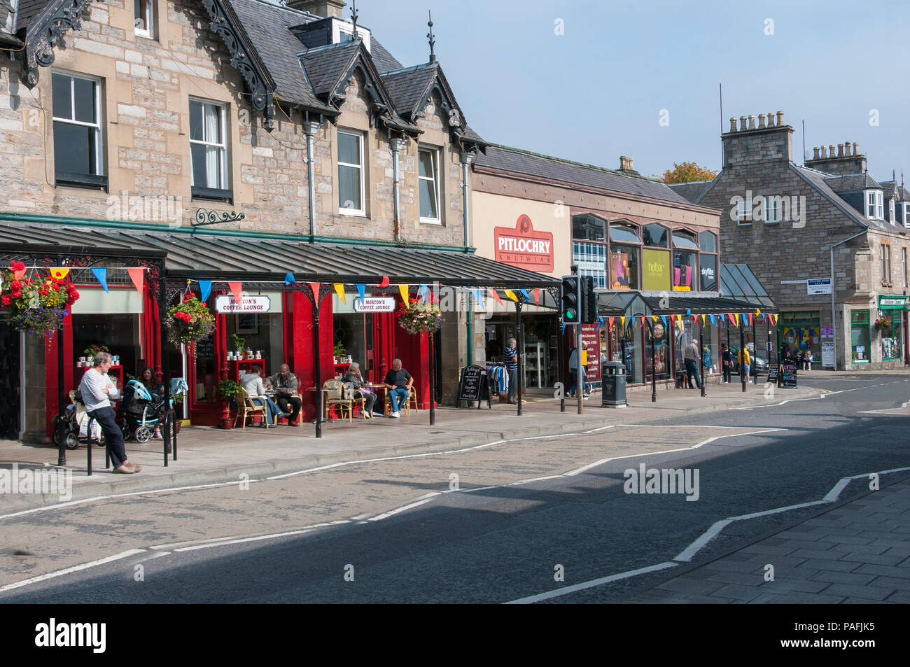 The busy main street with its mainly Victorian stone style buildings of shops, hotels, cafes, has an unusual period cast-iron canopy over one side Stock Photo