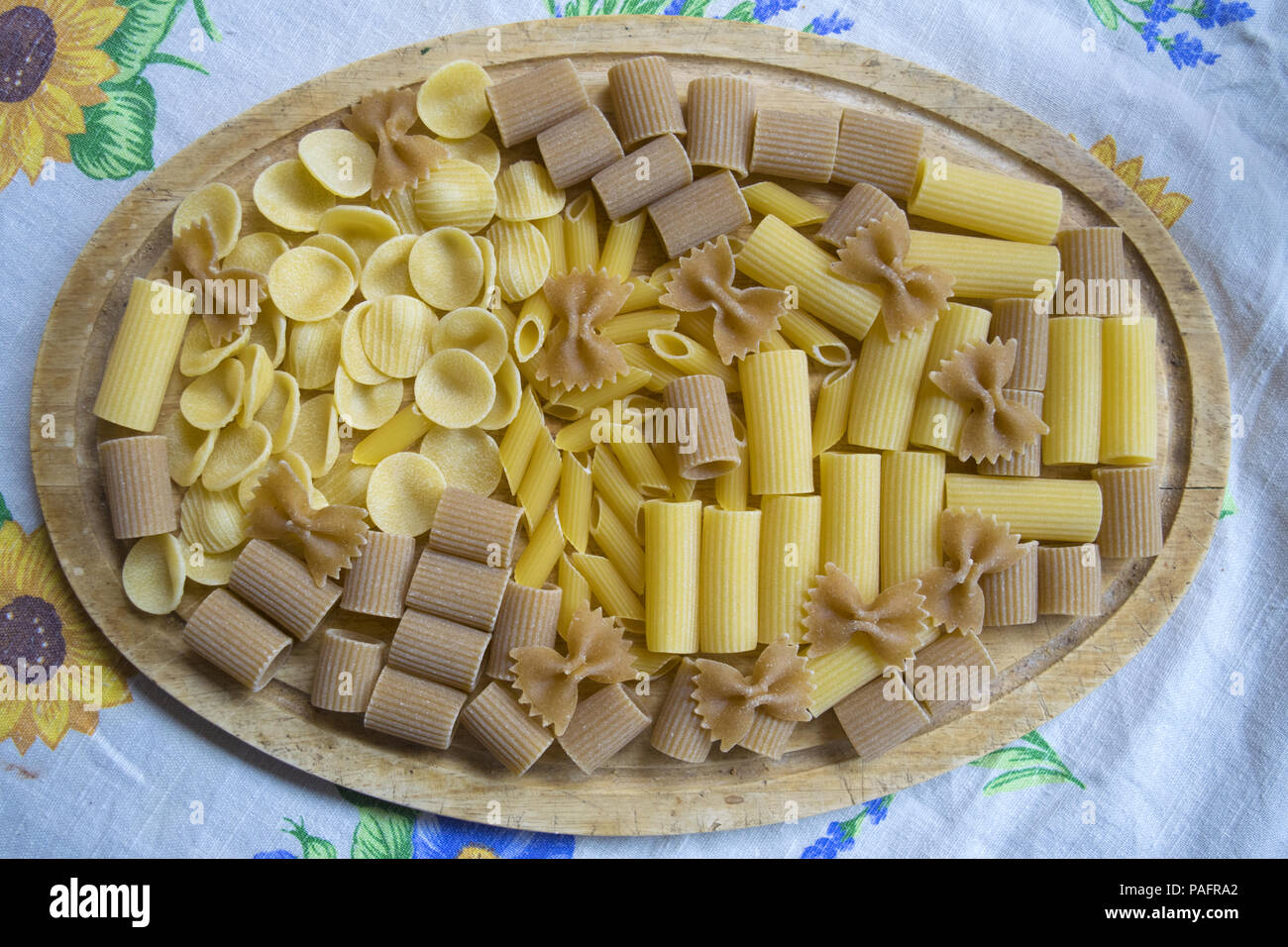 raw assorted wholemeal and normal pasta on a wooden dish Stock Photo