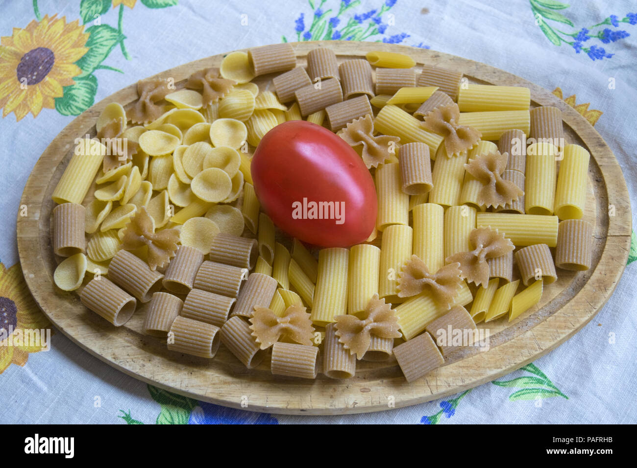 assorted wholemeal and normal raw pasta with a fresh tomato Stock Photo