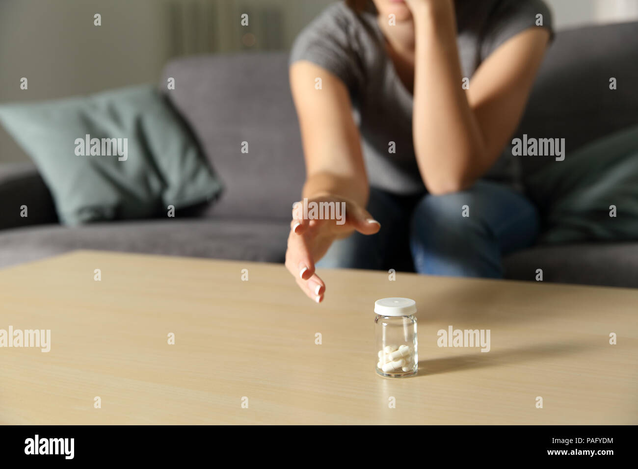 Close up of a woman hand reaching a bottle of painkiller capsules at home Stock Photo