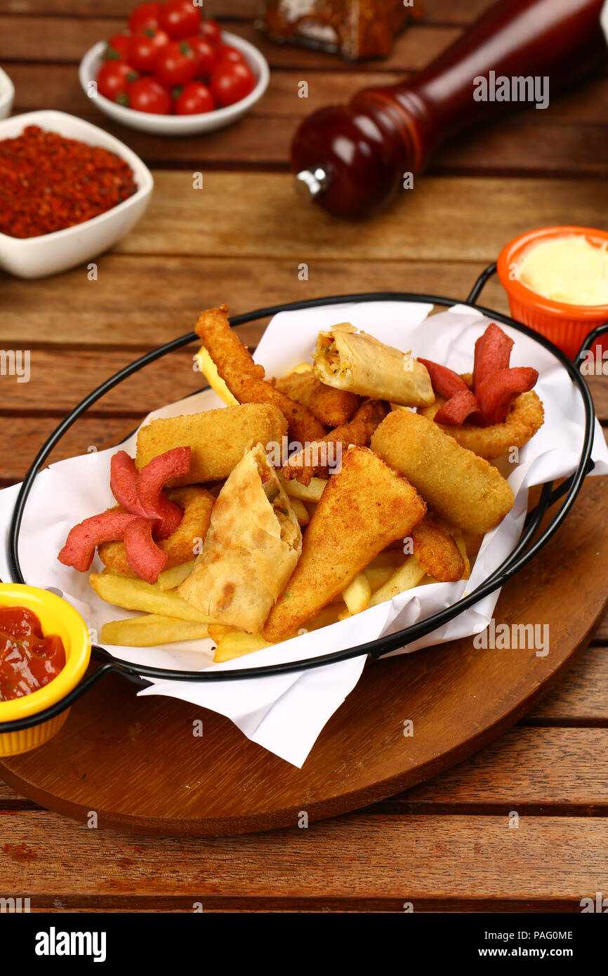 Mixed appetizer of french fries, fried sasusage, fried zucchini, pastry