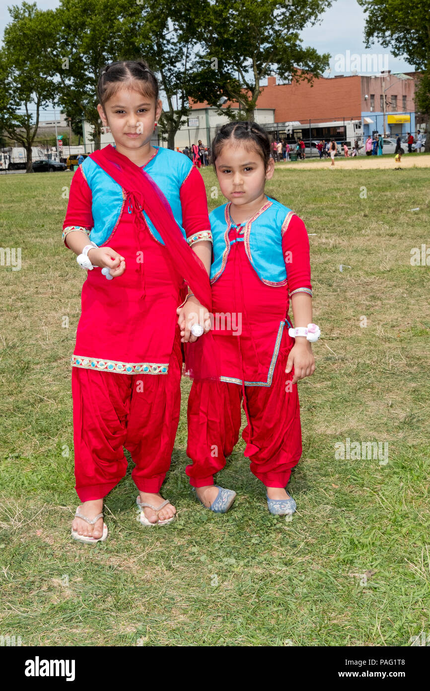 Posed portrait of nearly identically dressed sisters attending the Sikh