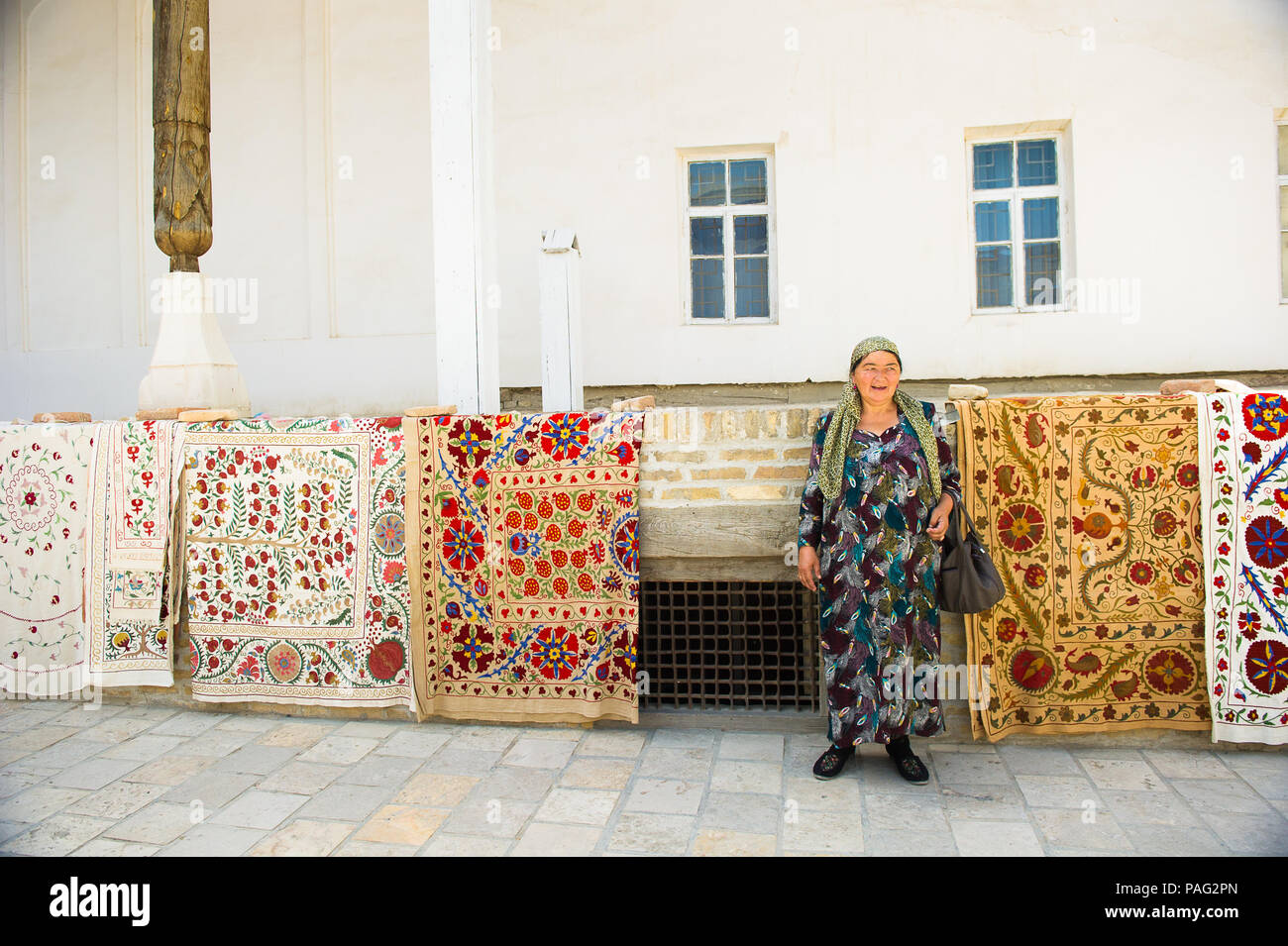 BUKHARA, UZBEKISTAN - JUNE 7, 2011: Unidentified Uzbek woman sells the carpets in Uzbekistan, Jun 7, 2011. 93% of Uzbek people consider that life in t Stock Photo