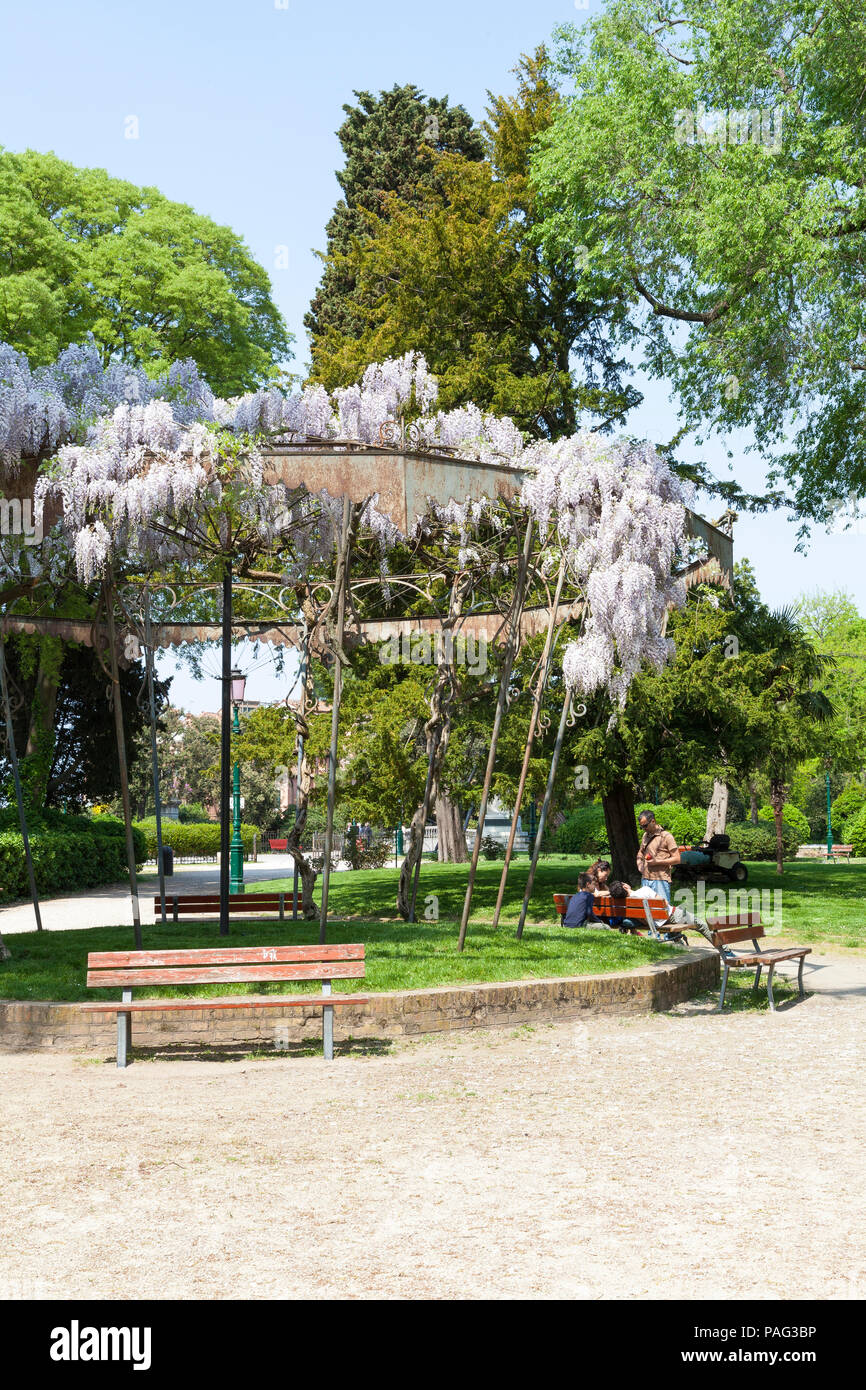 Wisteria covered bandstand in Giardini Pubblici, or Public Gardens, Castello, Venice, Veneto, Italy during spring with a family sitting eating lunch Stock Photo