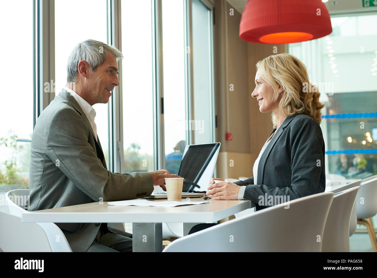 Businesspeople using laptop in cafeteria Stock Photo