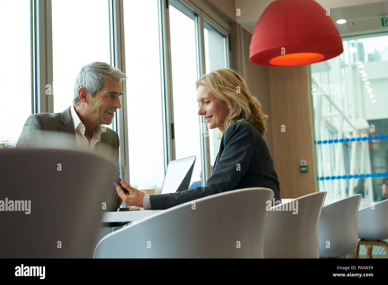 Businesspeople using smart phone in cafeteria Stock Photo
