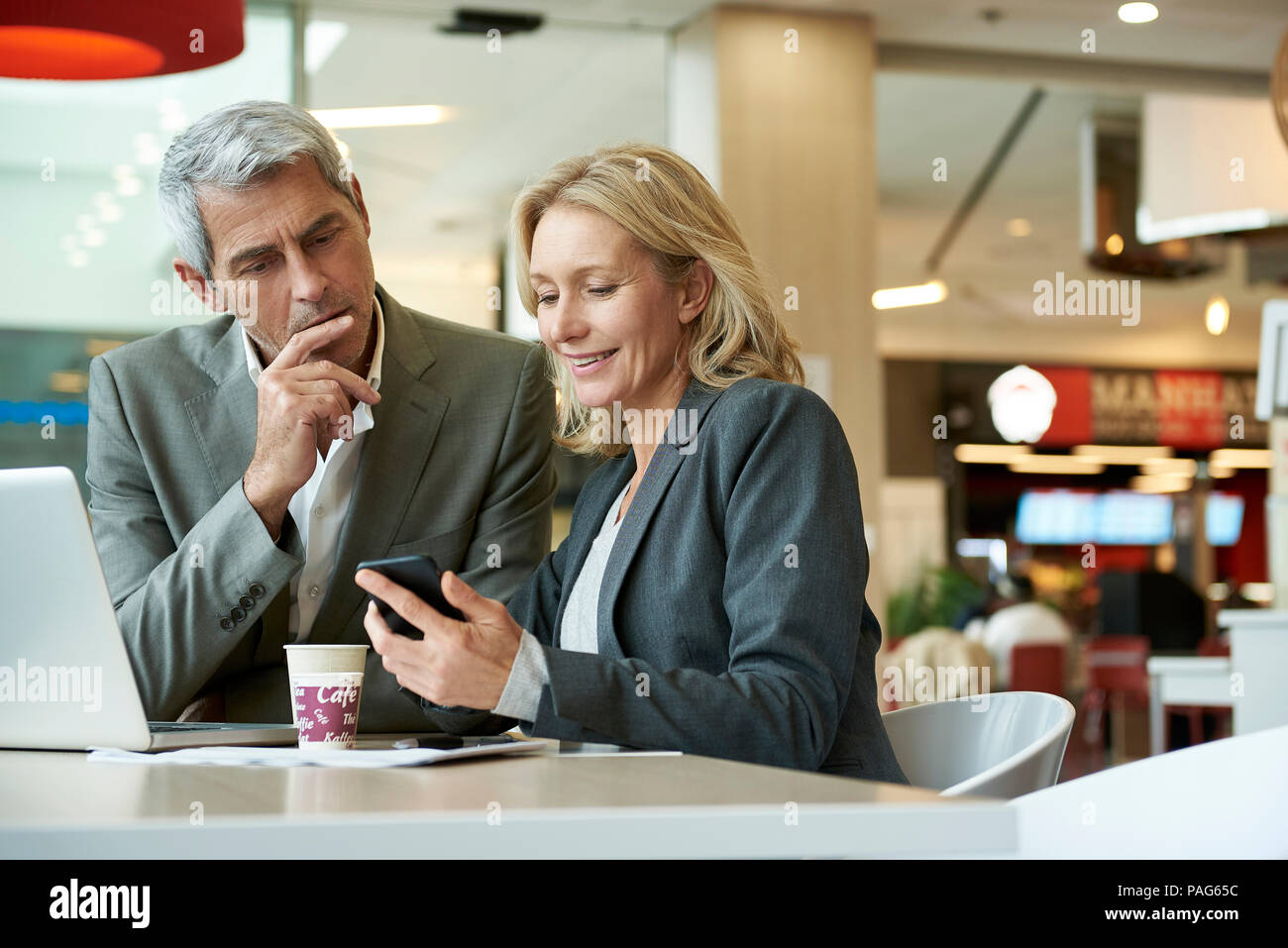 Businesspeople using smart phone in cafeteria Stock Photo