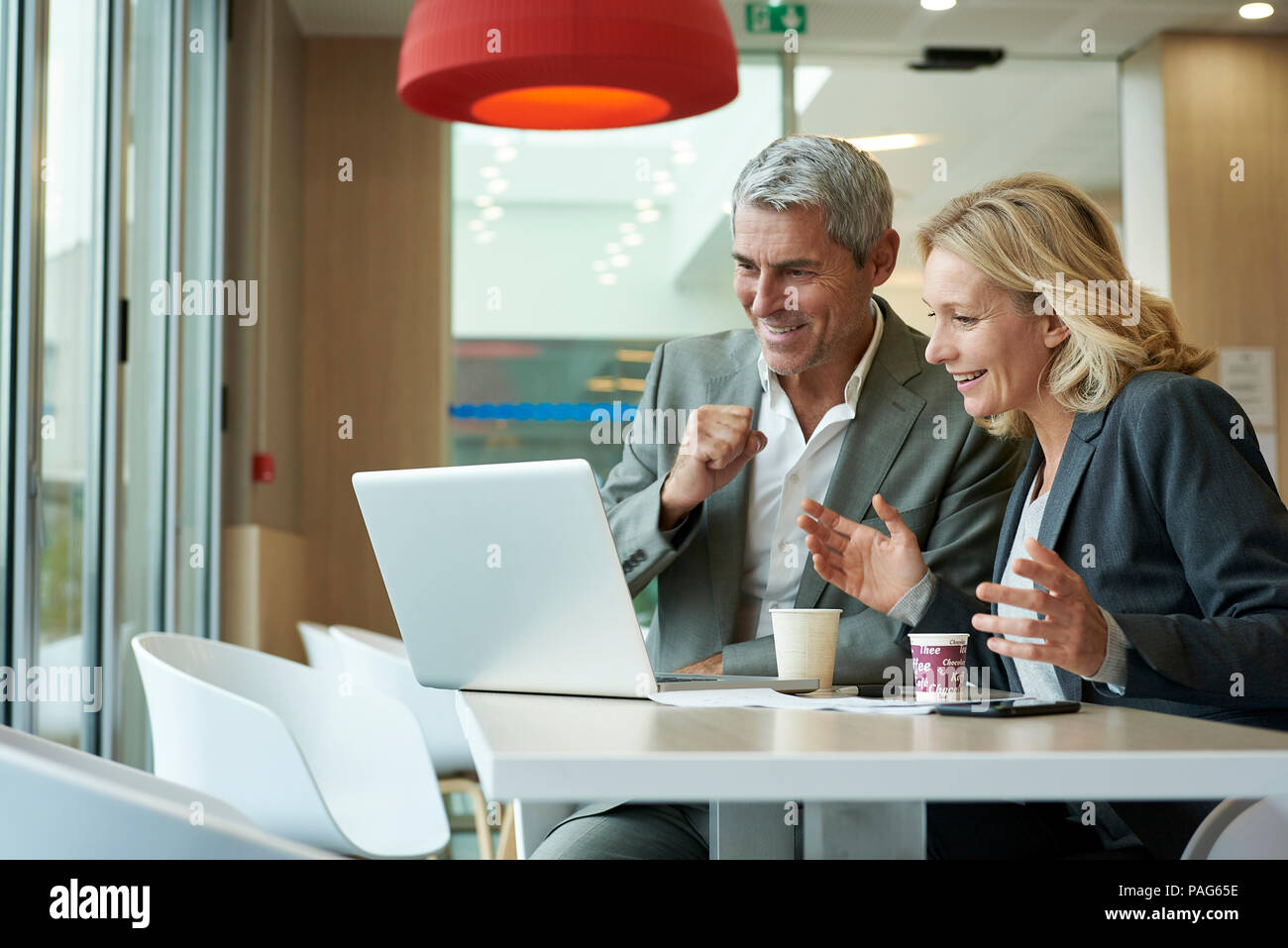 Businesspeople using laptop in cafeteria Stock Photo