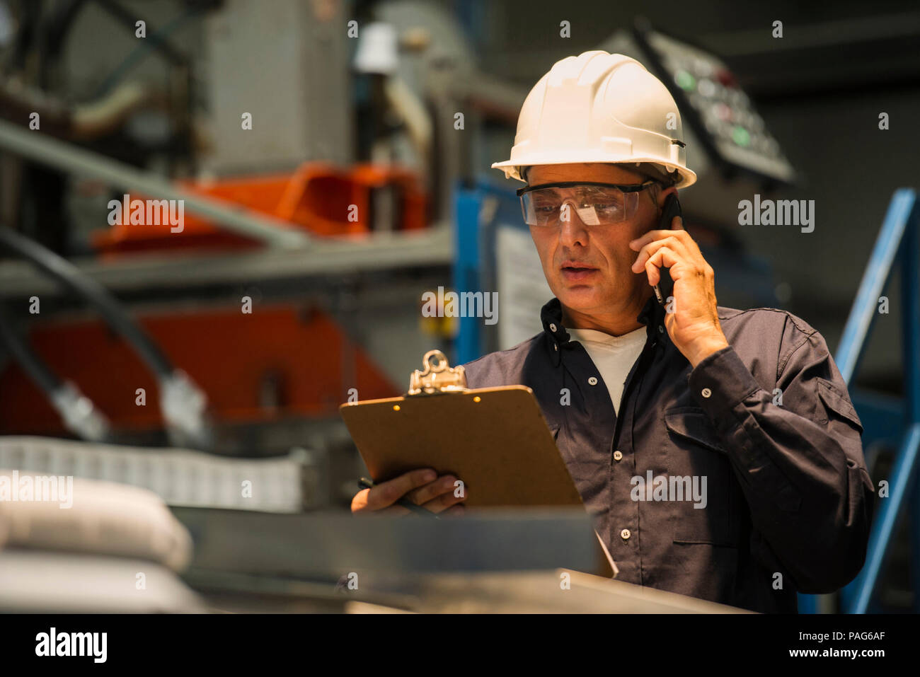 Factory worker using mobile phone in factory Stock Photo