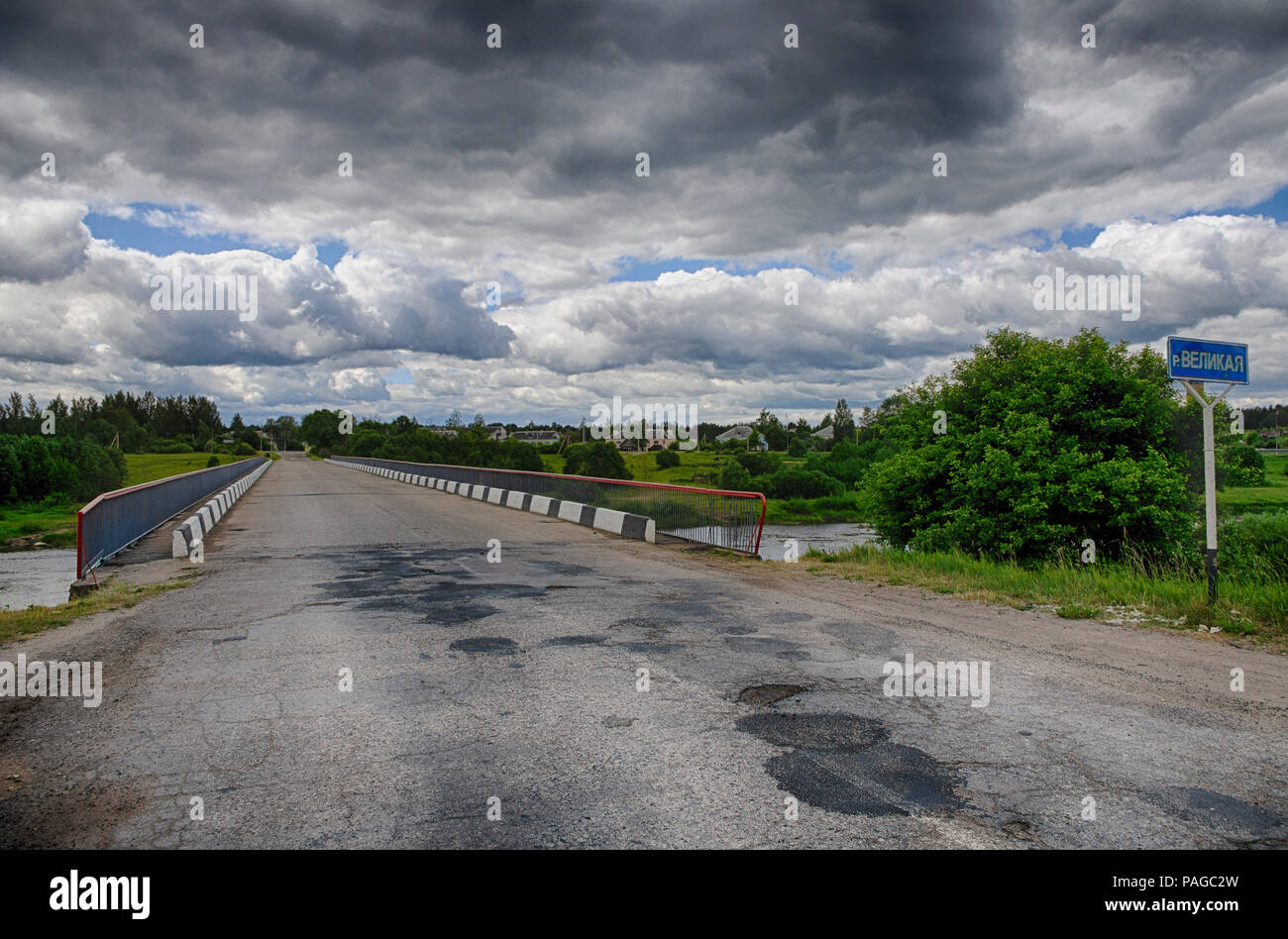 Summer landscape with dramatic sky and bridge over the river Velikaya in Pskov region (Russia) Stock Photo