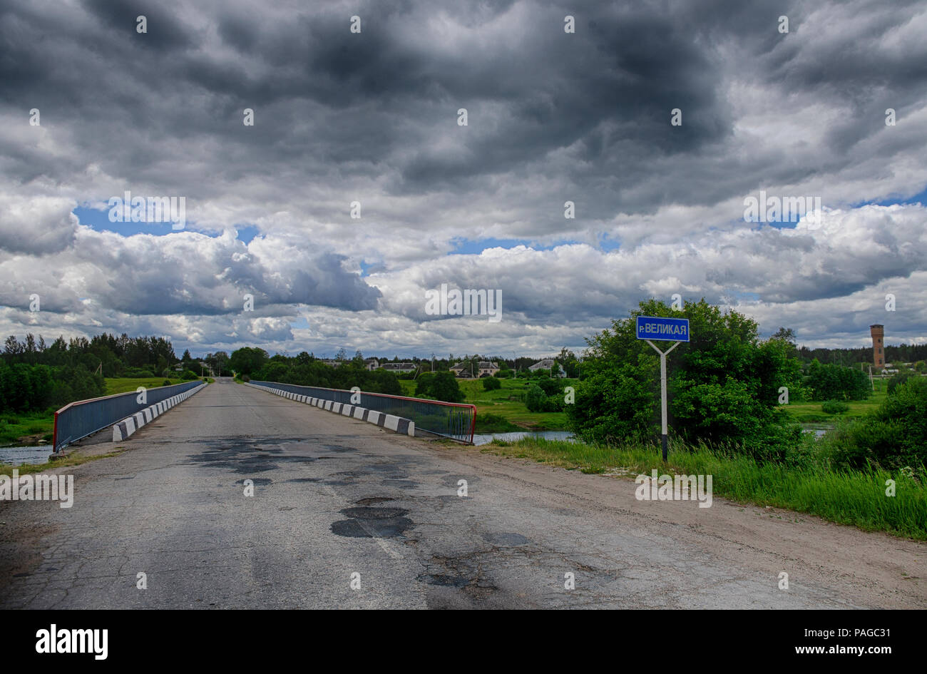 Summer landscape with dramatic sky and bridge over the river Velikaya in Pskov region (Russia) Stock Photo