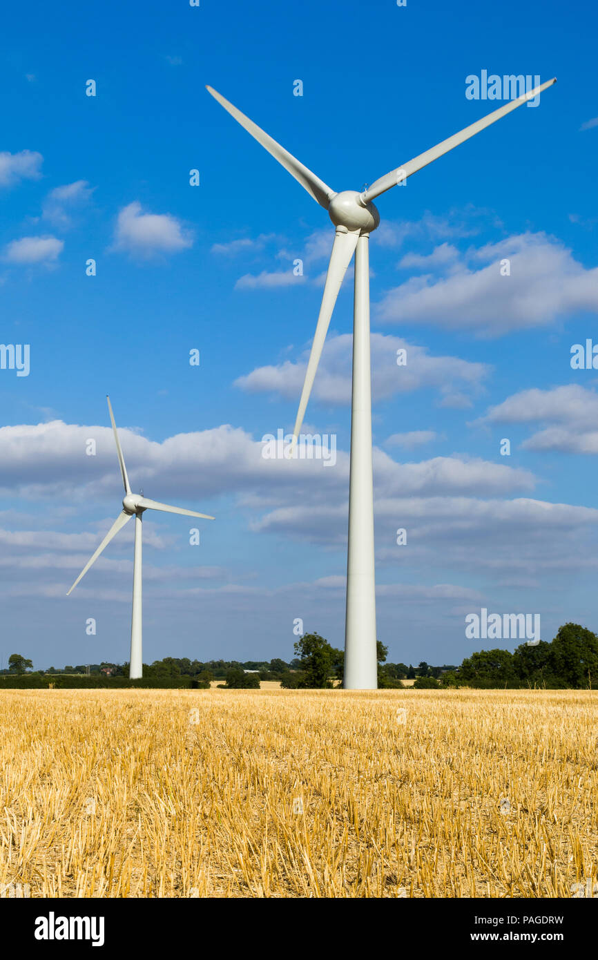Wind Farm Turbines, Wheat field, blue skies, white fluffy clouds green trees in the background. Six Hills nr Loughborough Leicestershire England UK. Stock Photo