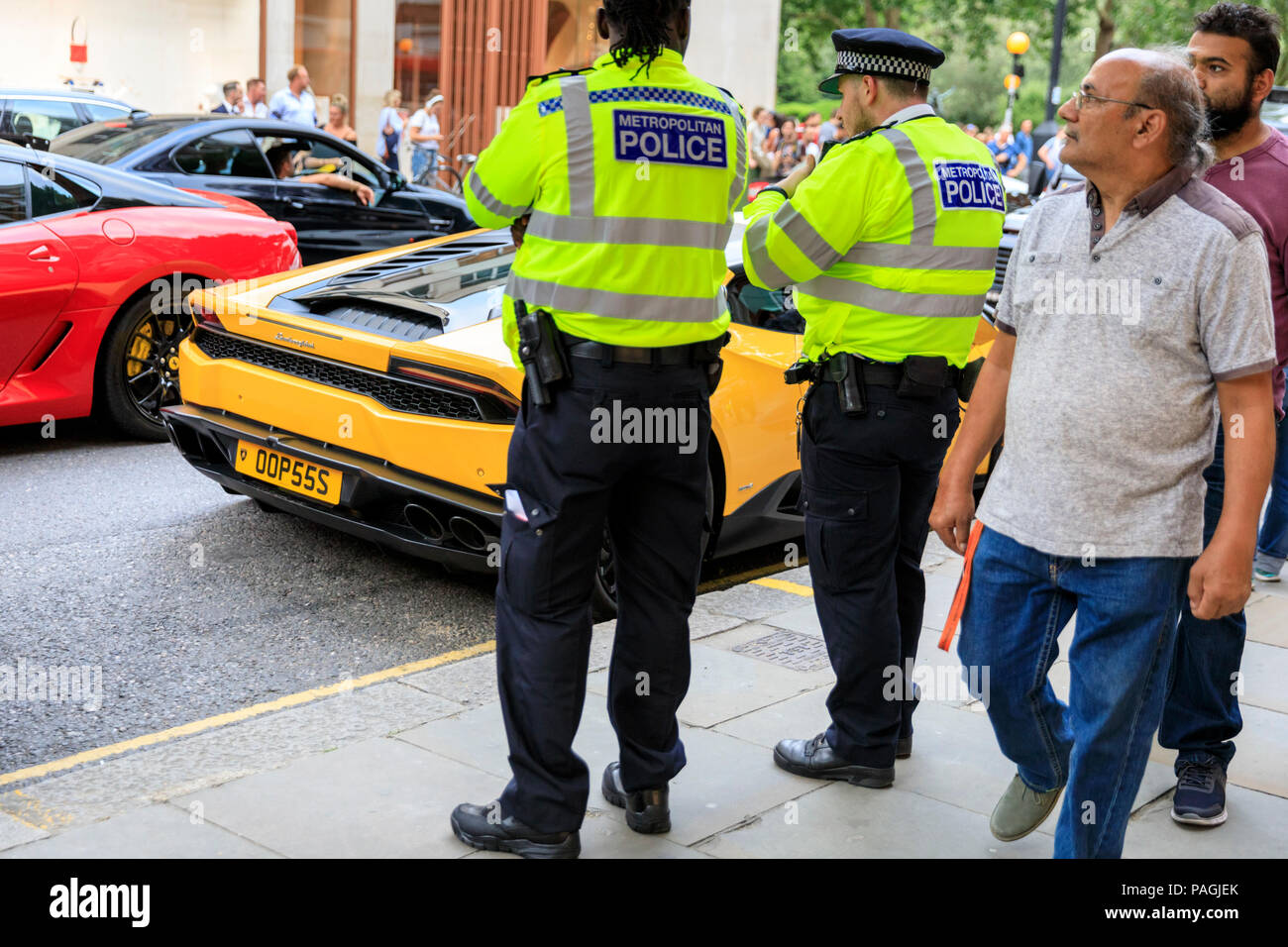 Sloane Street, London, UK, 20th July 2018. Two policemen look at a  Lamborghini, it's numberplate reading OOPSSS.. Supercars,  high-performance and classic cars, as well as some characterful adaptions,  line up and drive