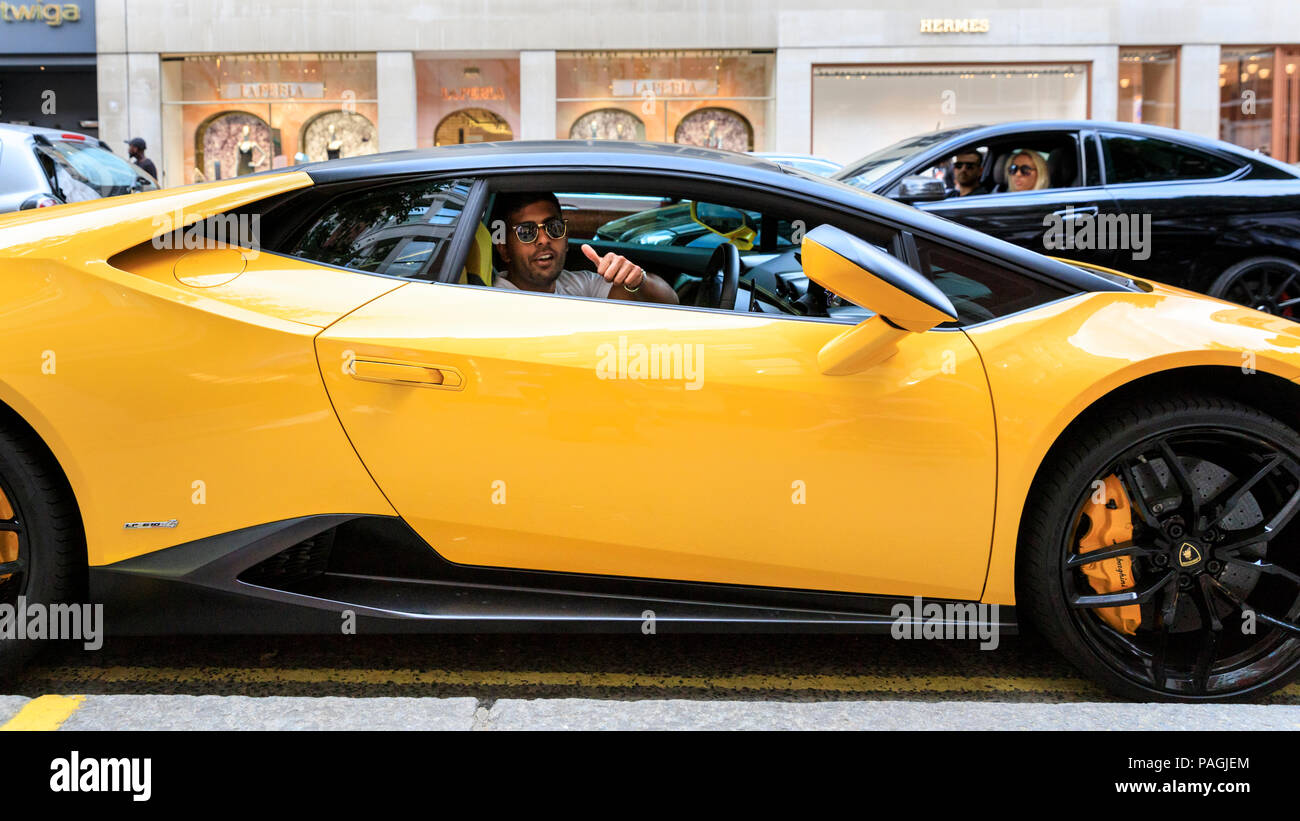 Sloane Street, London, UK, 20th July 2018. The driver of a yellow  Lamborghini gives the event the thumbs up. Supercars, high-performance and  classic cars, as well as some characterful adaptions, line up