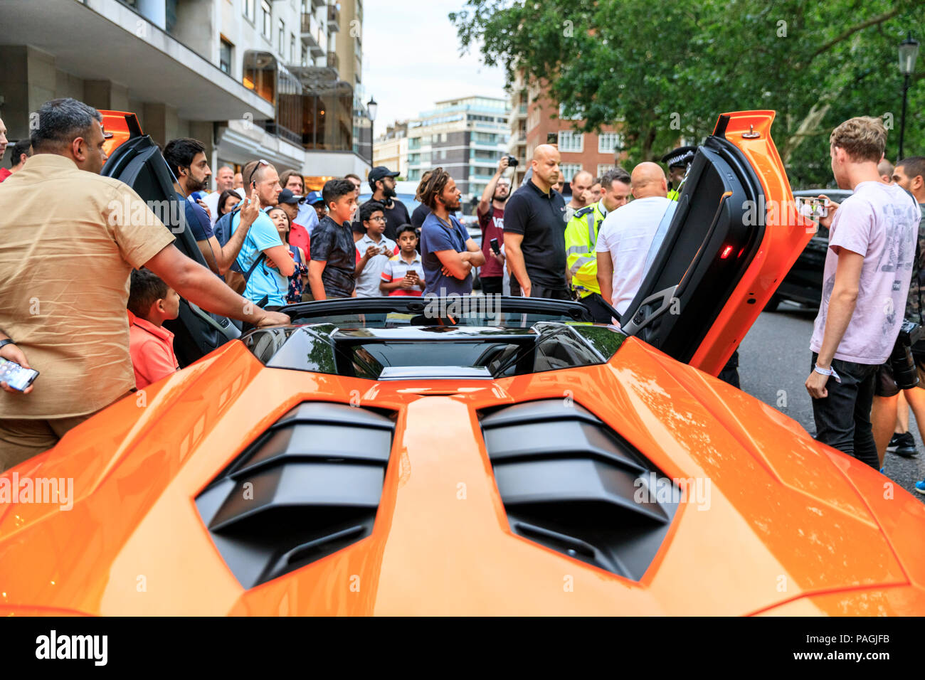 Sloane Street, London, UK, 20th July 2018. Police stop, then talk to the  upset owner of this orange Lamborghini, whilst a crowd grows around the  car. Supercars, high-performance and classic cars, as