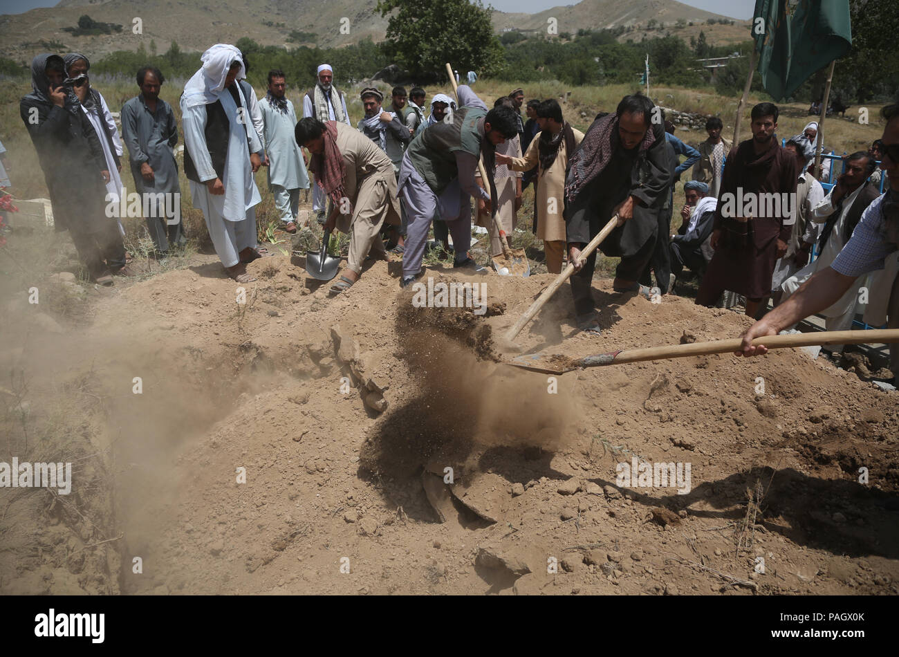 Kabul, Afghanistan. 23rd July, 2018. Friends and relatives throw earth on the tomb of a suicide attack victim in Kabul, capital of Afghanistan, July 23, 2018. At least 14 people were killed and over 60 wounded on Sunday after a suicide bomber detonated his suicide vest near Kabul airport shortly after convoy of First Vice President General Abdul Rashid Dostum passed by the area, Kabul police said Monday. Credit: Rahmat Alizadah/Xinhua/Alamy Live News Stock Photo