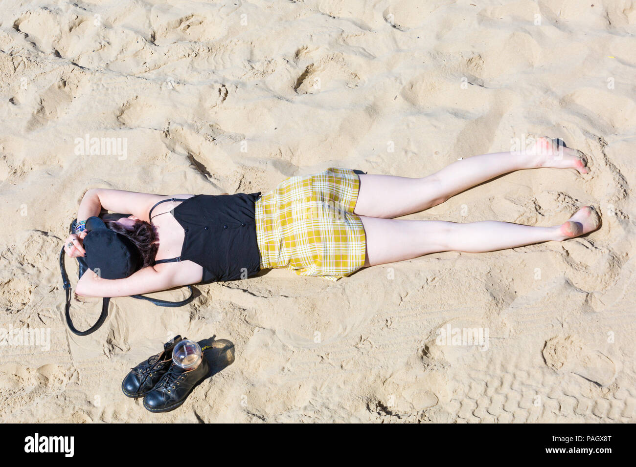 Bournemouth, Dorset, UK. 23rd July 2018. UK weather: the heatwave continues as temperatures rise on a scorching hot and sunny day at Bournemouth beaches with blue skies and unbroken sunshine. Sunseekers head to the seaside to soak up the sun. Woman sunbathing on the beach. Credit: Carolyn Jenkins/Alamy Live News Stock Photo