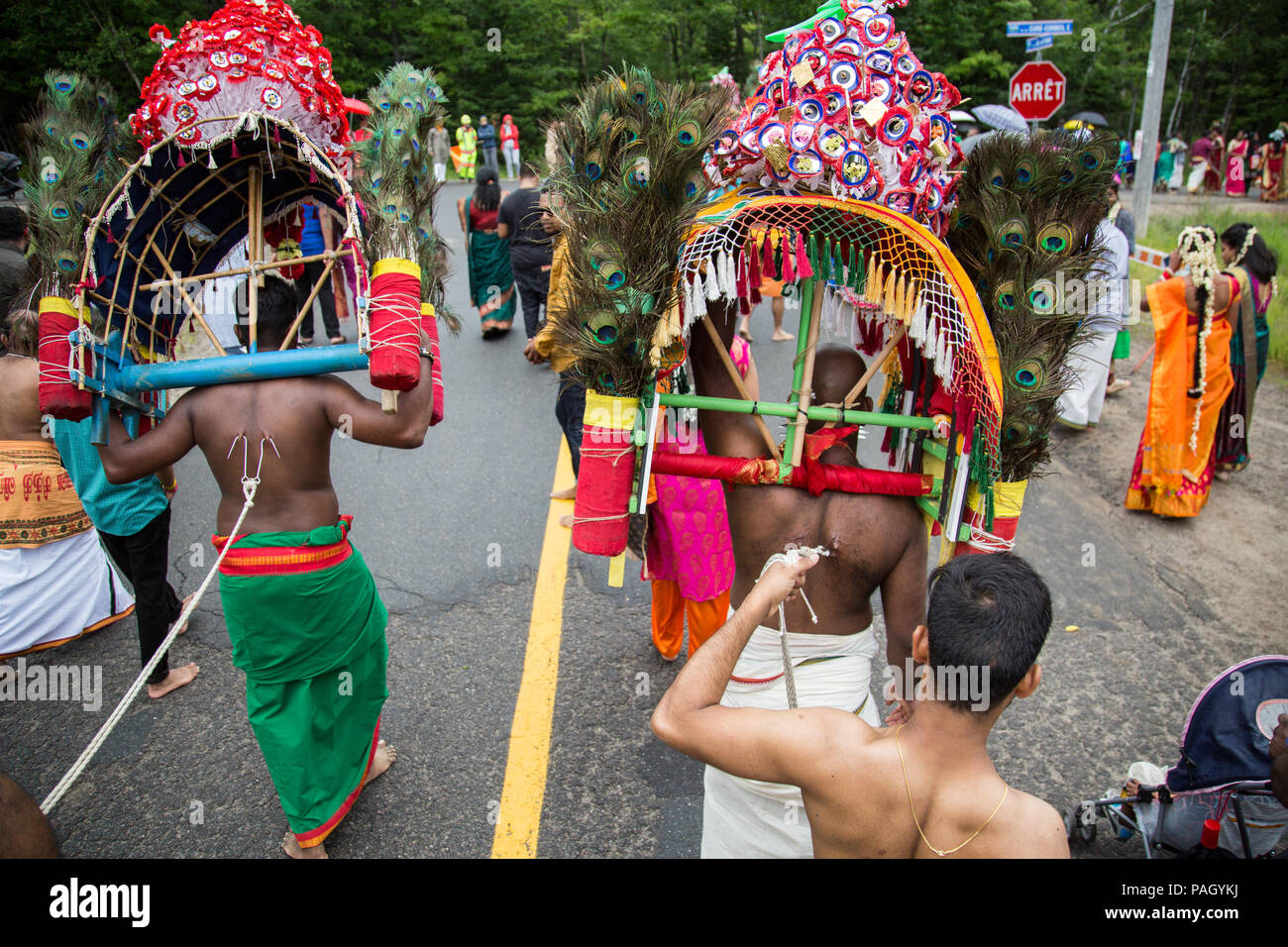 Val-Morin, Canada, July 22, 2018. Hindu devotees carrying kaavadis on their shoulders while hooks are piercing their skin at the Kaavadi festival in Val Morin, Quebec. Hundreds of Hindu devotees gathered for the annual celebration of Lord Subramanya (or Muruga), the Hindu god of war. Several devotees are suspended by hooks and needles are piercing their skin as a way to show penance and transcendence. Credit: Cristian Mijea/Alamy Live News. Stock Photo