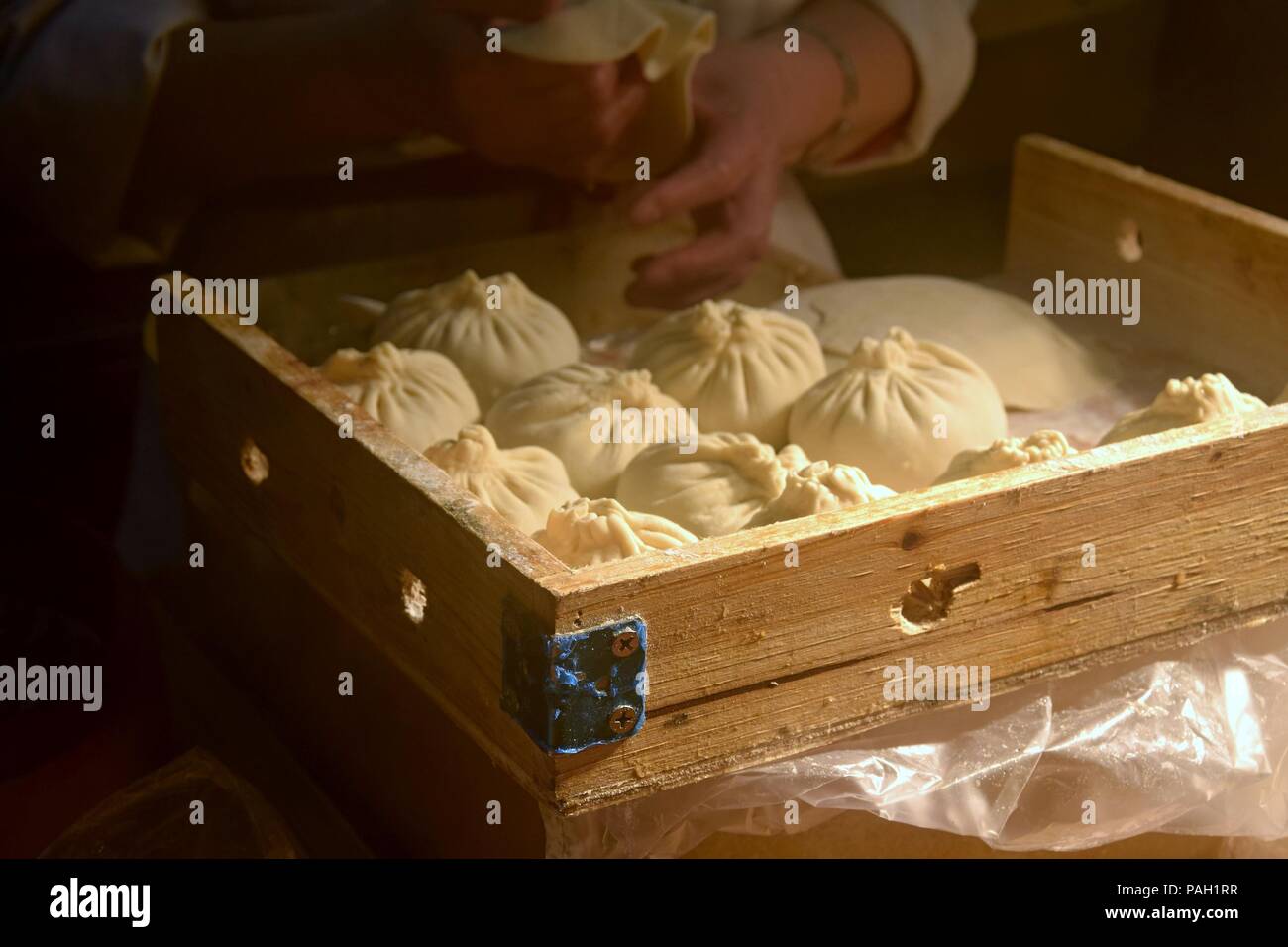 A woman makes yeast chinese dumplings "bao zi" stuffed with meat and