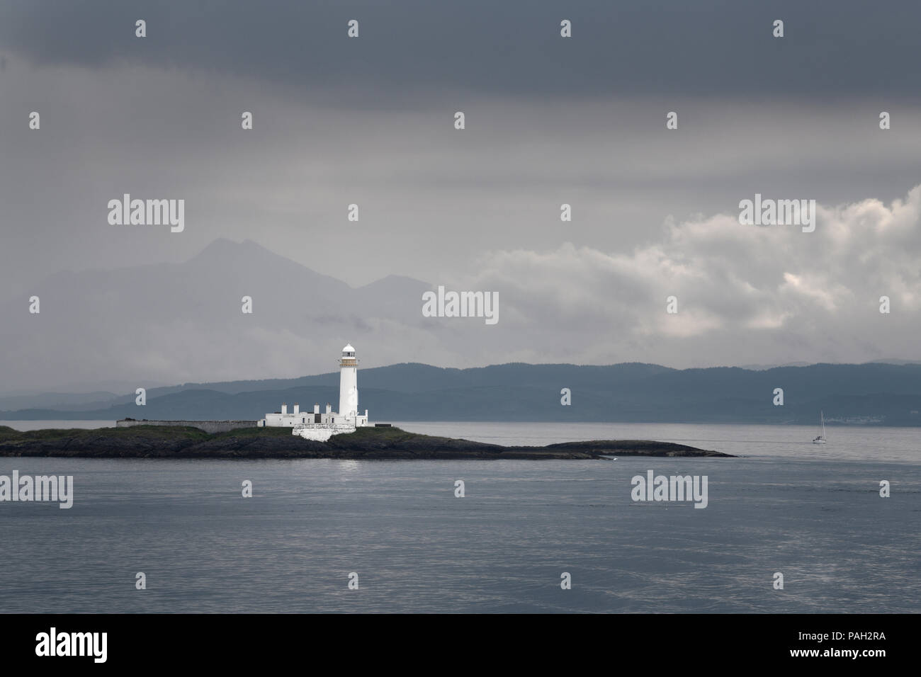 Lismore Lighthouse on Eilean Musdile Islet off Lismore Island with rain and clouds over the west coast highlands Scotland UK Stock Photo