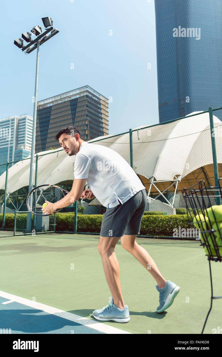 Young man playing tennis outdoors in a modern district of the city Stock Photo