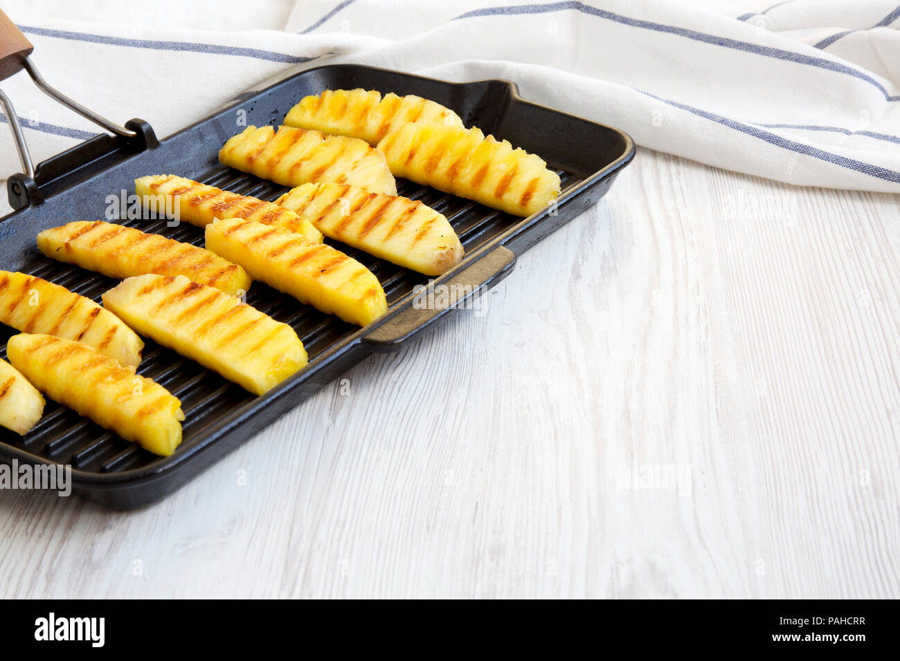 Grilled pineapple wedges in grilling pan, side view. Summer food. Close