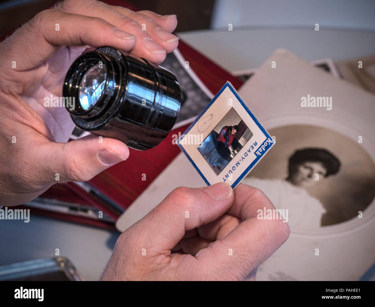 OLD FAMILY PHOTOGRAPHS Man sorting through historic family ephemera, documents, photo albums and colour transparencies with eye glass lupe Stock Photo