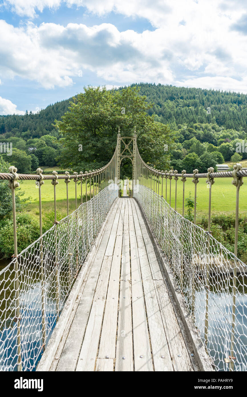 Rickety wooden footbridge over the River Conwy, with green trees, hills and water Stock Photo