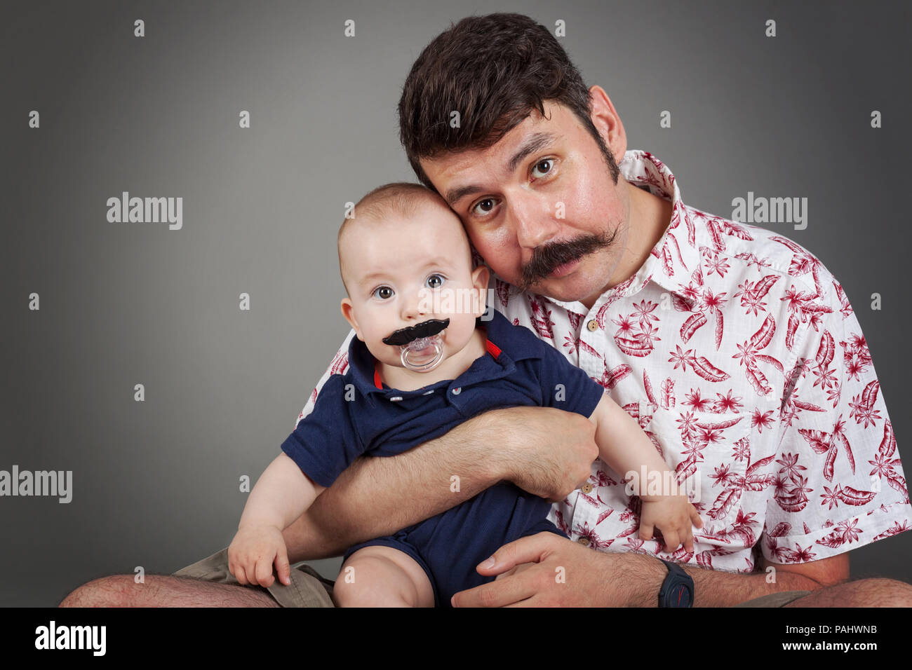 Handlebar Mustache family tradition-Funny portrait of Father and a son both with Handlebar mustaches, looking surprised towards the camera, horizontal Stock Photo