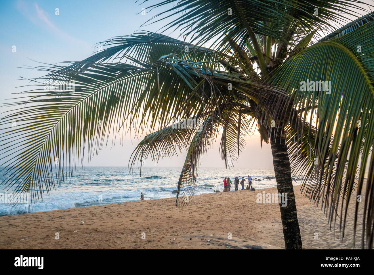 A group of people hangout on the beach looking out into the waves Monrovia, Liberia Stock Photo