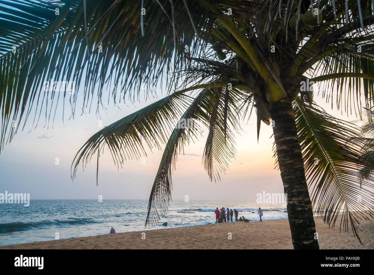 A group of people hangout on the beach looking out into the waves Monrovia, Liberia Stock Photo
