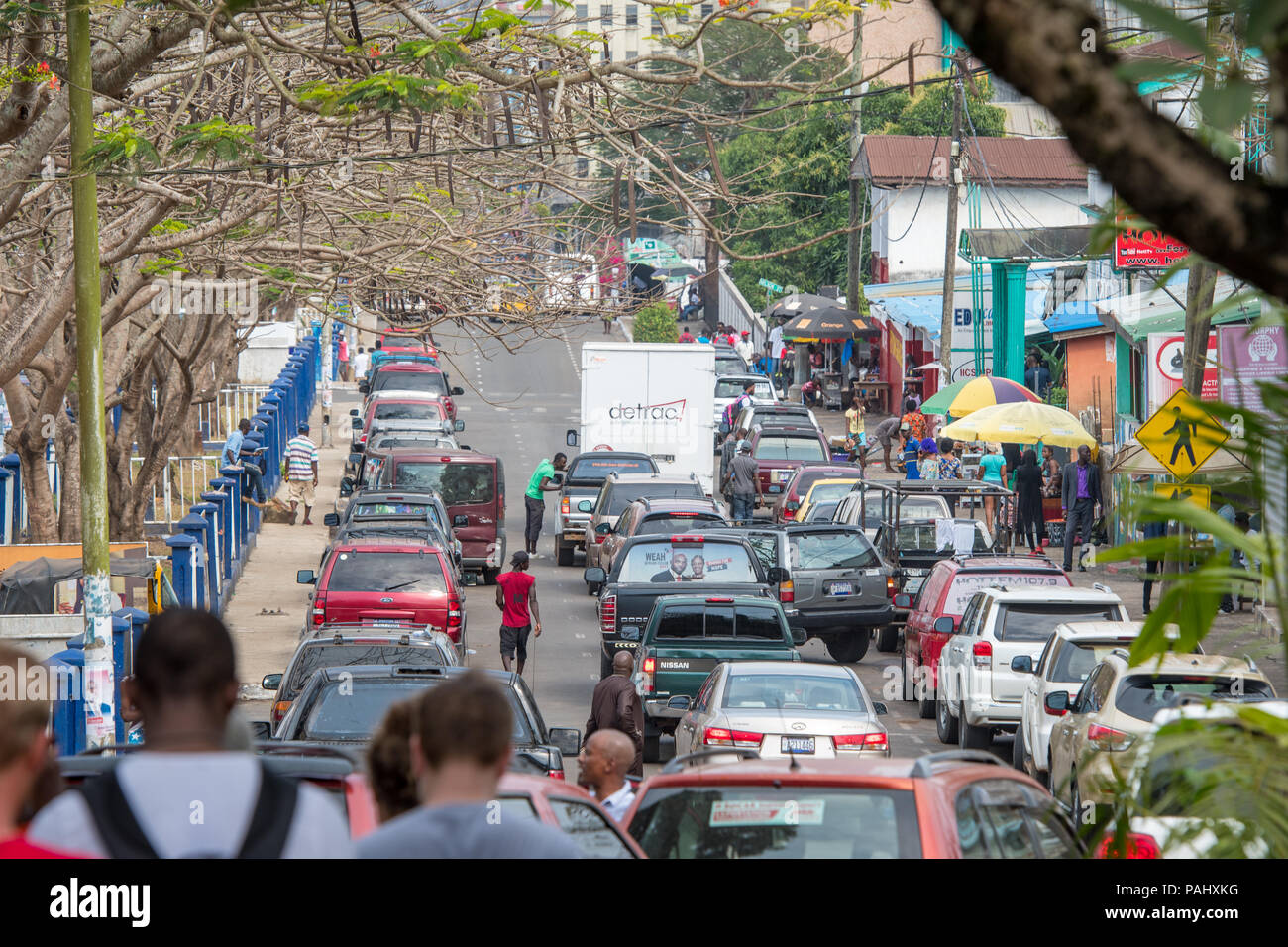 Cars drive down a crowded street in the bustling city of Monrovia, Liberia Stock Photo