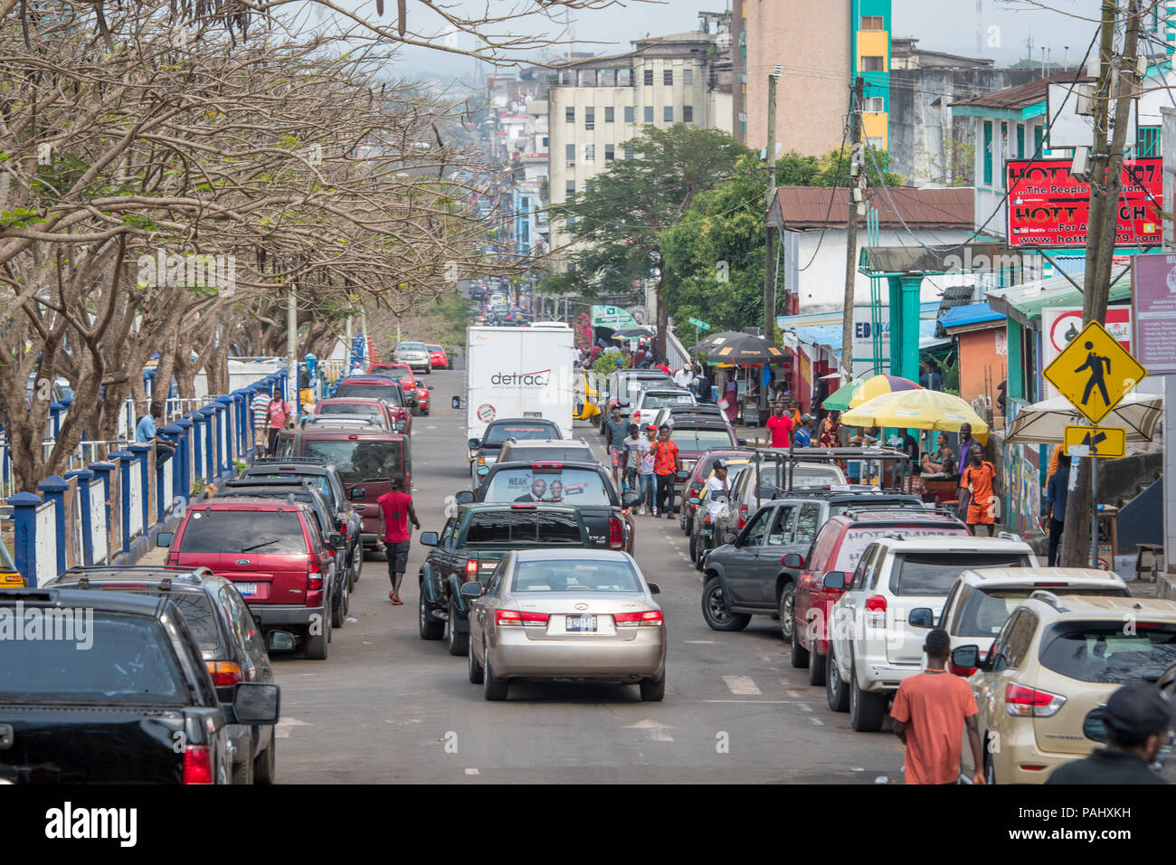 Cars drive down a crowded street in the bustling city of Monrovia, Liberia Stock Photo