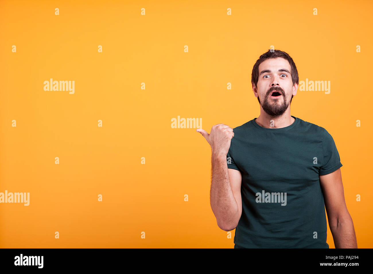 Surprised emotional adult man pointing at the copyspace which in available for your text, advertisement or promotions. Amazement and enthusiasm concept Stock Photo