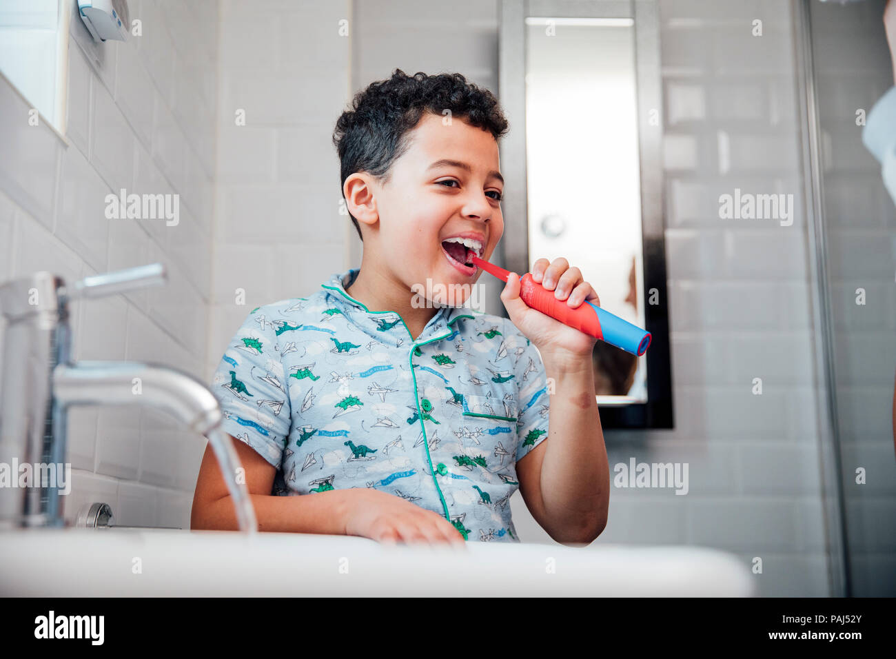 Little boy is brushing his teeth at the bathroom sink in the morning. Stock Photo