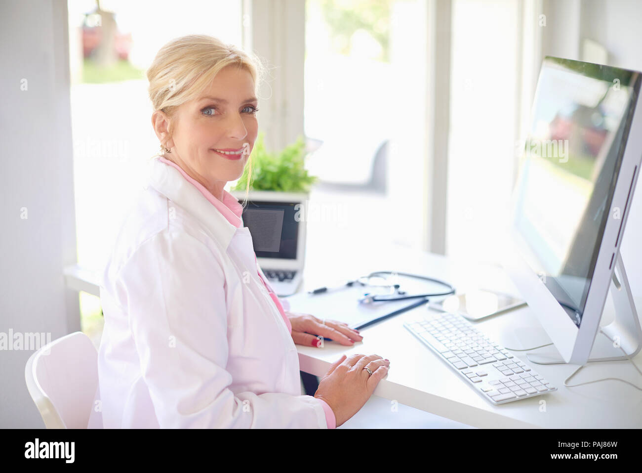 Smiling senior female research physician using computer and laptop ...