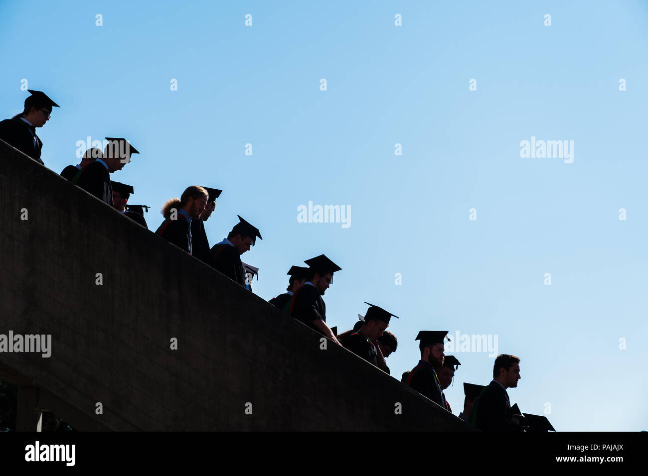 Higher Education in the UK: Students graduating from Aberystwyth university, in their traditional mortar boards and black academic gowns.  Silhouetted against a blue sky. July 2018 Stock Photo