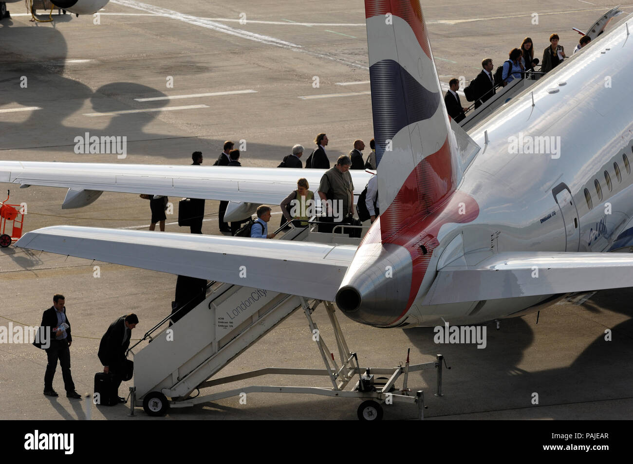 passengers with carry-on bags boarding by airstairs a British Airways BA CityFlyer Embraer 170STD parked at London City Stock Photo