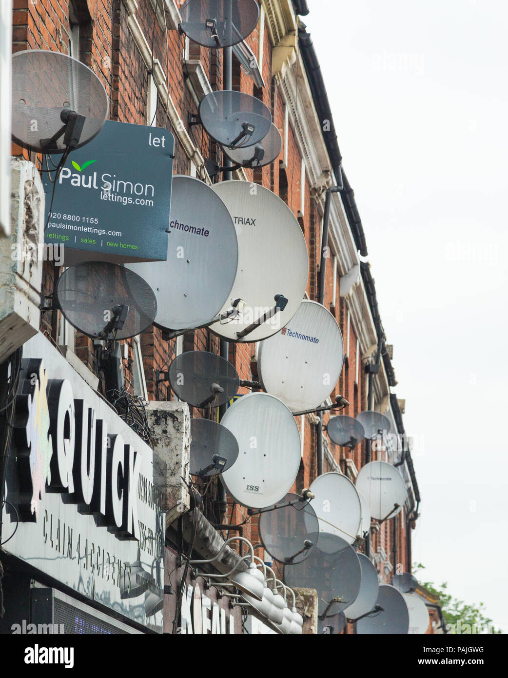 A mass of satellite dishes on the exterior walls of flats above shops