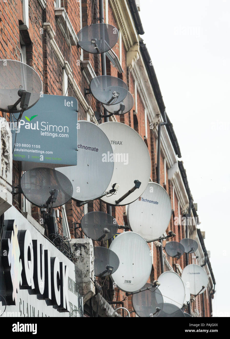 A mass of satellite dishes on the exterior walls of flats above shops