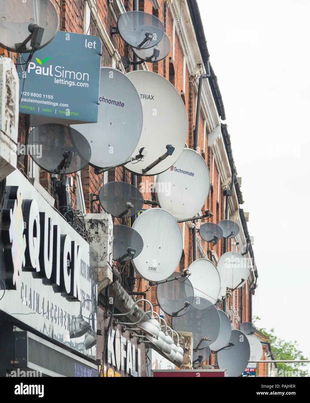 A mass of satellite dishes on the exterior walls of flats above shops